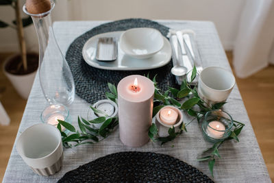Large candle on a romantic dinner table set up at home for two