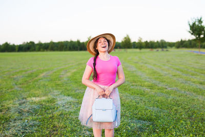 Full length of smiling young woman standing on field