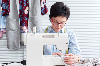 Craftswoman sewing textile on machine at workshop