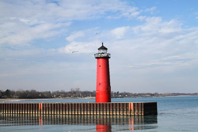 Lighthouse by sea against sky