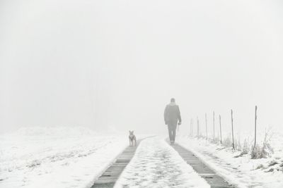 Rear view of people walking on snow covered road