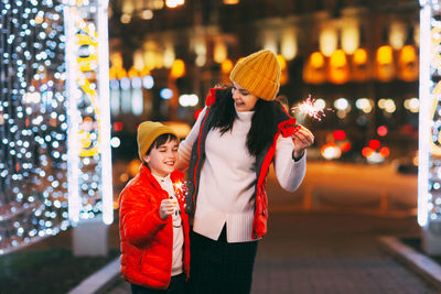 A beautiful boy and his mother celebrate new year or christmas with sparklers