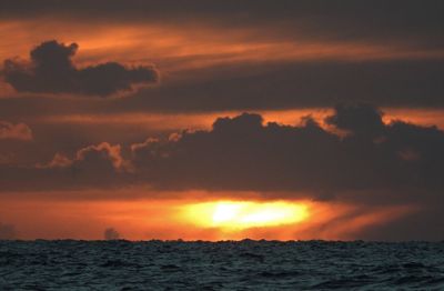 Scenic view of sea against dramatic sky during sunset