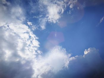 Low angle view of sunlight streaming through clouds