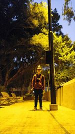 Full length of man sitting on sidewalk against trees