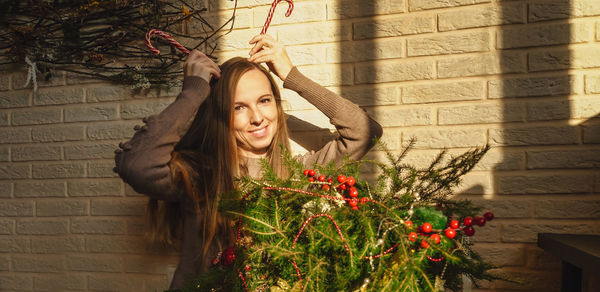 Portrait of young woman standing against wall