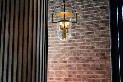 Low angle view of illuminated light bulb hanging on wall