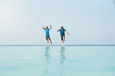 People enjoying in sea against clear sky