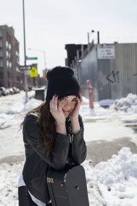 Young woman using phone while standing on snow