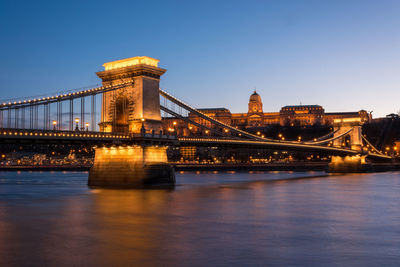 Illuminated chain bridge over danube river in city at night