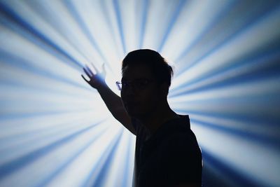Portrait of man standing against light beams