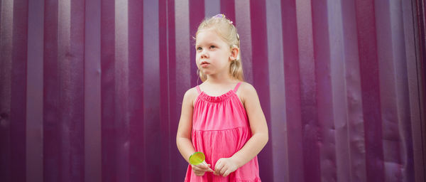 Portrait of young woman standing against red curtain