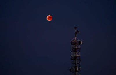 Low angle view of communications tower against sky at night