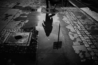 Reflection of person on puddle at street