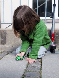 Girl playing with toy car on footpath
