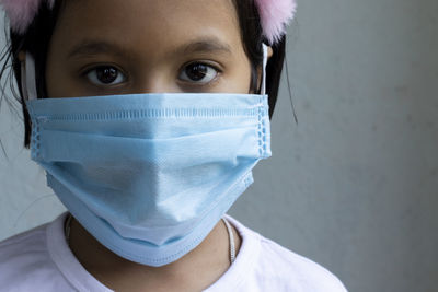 An indian girl child wearing surgical nose mask looking at camera for corona virus or covid-19