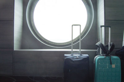 Two suitcases for traveling in front of the round porthole of the ship