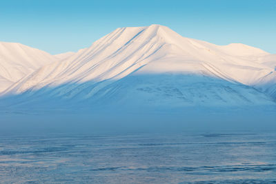 Scenic view of snowcapped mountains against clear blue sky