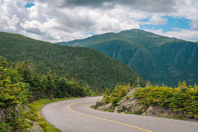 Scenic view of road by mountains against sky