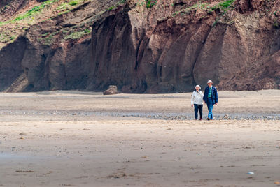 Men walking on rocks by land