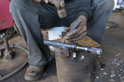 Midsection of man working on metal