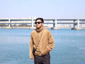 Portrait of young man standing against sea