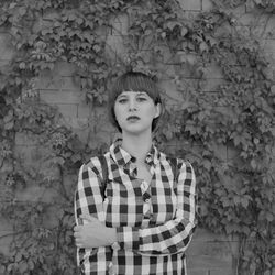 Portrait of young woman standing against stone wall