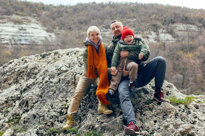 Family with a child sitting on a rock in autumn