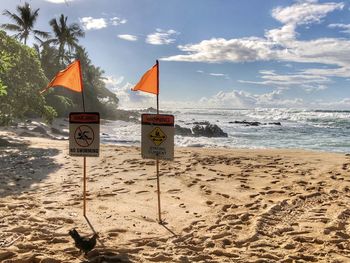 Information sign on beach against sky