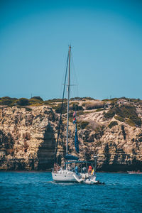 Sailboat sailing on sea against clear blue sky