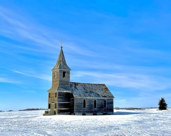 Built structure on snow covered landscape against sky