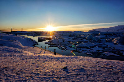 Scenic view of snow covered land against sky during sunset