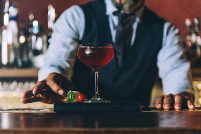Midsection of bartender preparing cocktail in bar