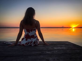 Woman standing at beach against clear sky during sunset