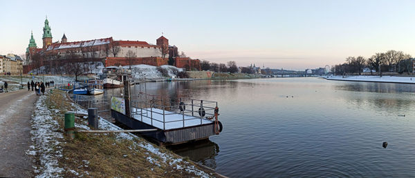 Scenic view of river by buildings against sky