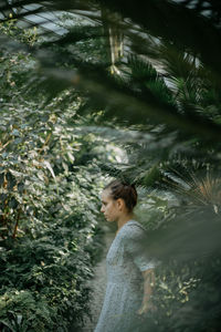Side view of young woman standing in forest