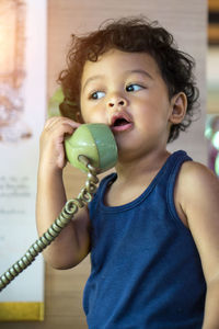 Cute boy talking on telephone at home