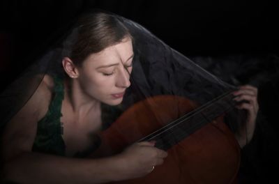 Woman playing cello against black background