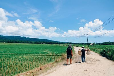 Men working on agricultural field against sky