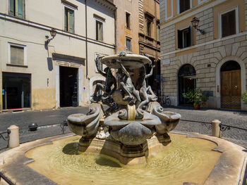 Statue by fountain against buildings in city