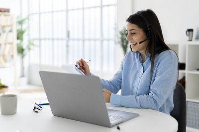 Young woman using mobile phone while sitting on table