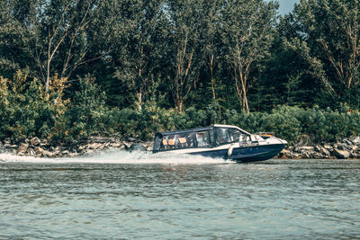 Boat sailing in river by trees in forest