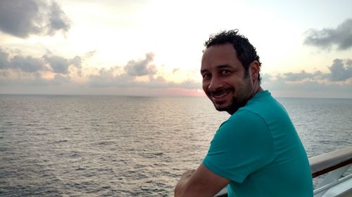 Portrait of smiling man standing in cruise ship on sea during sunset