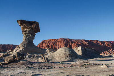 Rock formations on landscape against clear blue sky