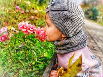 Close-up of girl smelling pink flowers outdoors