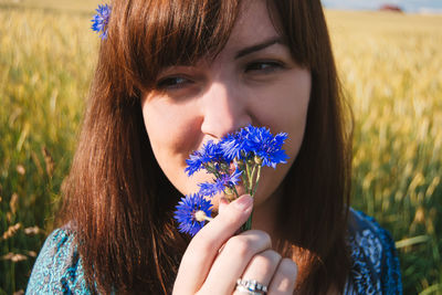 Close-up portrait of smiling young woman with flowers in field