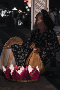 Midsection of woman holding hat in city