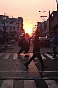 Silhouette of people walking on city street at sunset