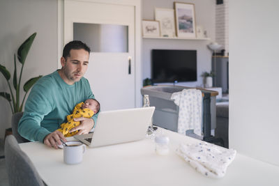 Full length of man sitting at table at home