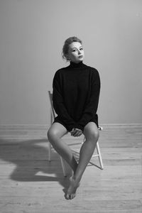 Portrait of young woman standing against wall